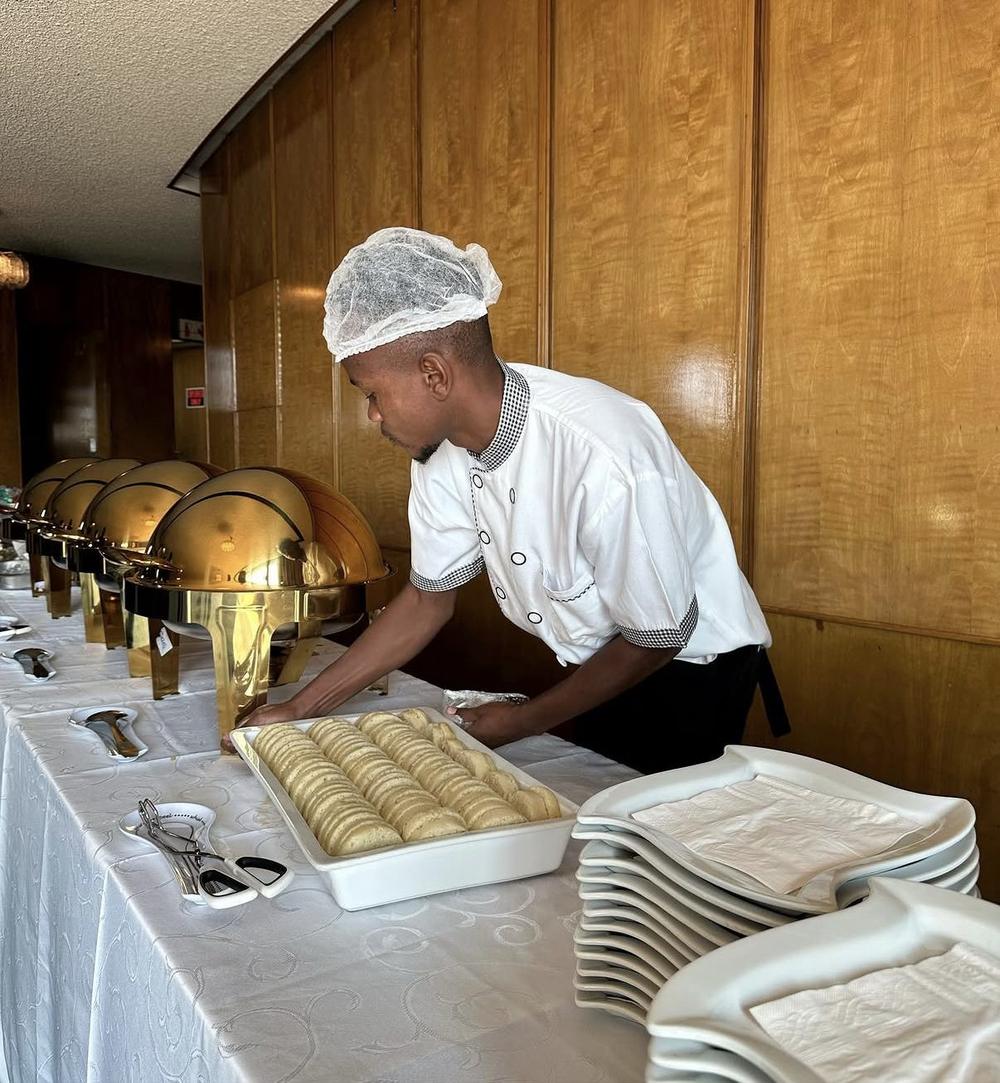 Mazz Catering chef arranging a buffet beside gold chafing dishes