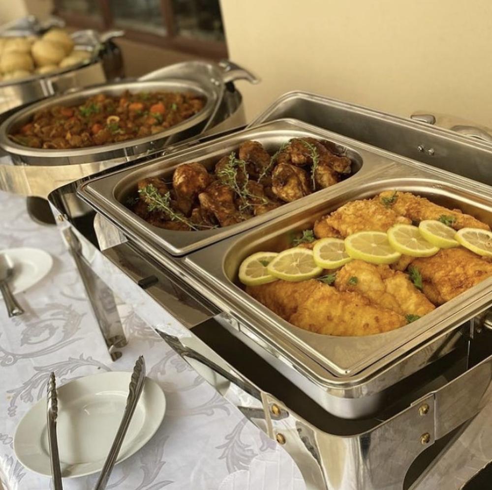Chafing dishes with chicken pieces and lemon-topped fish