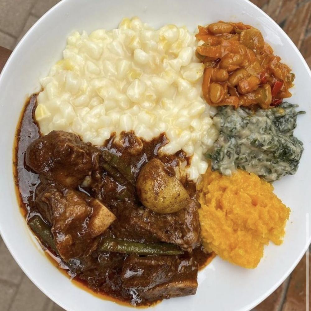 Plate of beef stew with samp, chakalaka, creamed spinach and butternut